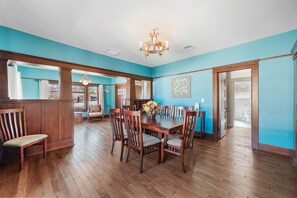 Comedor con mesa y sillas de madera, una araña y pared azul.