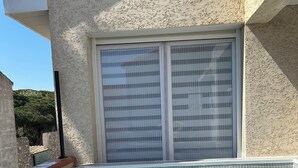 A swimming pool with tiled steps and a window with blinds.