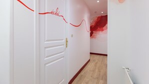 Ein Flur mit einer weißen Tür, einer roten Linie an der Wand und einem roten, abstrakten Wandbild.