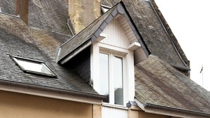 Ein Gebäude mit einer beige farbenen Fassade, einer weißen Tür und zwei Fenstern mit Rollläden.