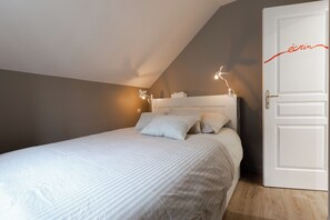 A bedroom with a bed, pillows, a nightstand, and a door. - Superb 3-star gîte, parking space in front of the gîte. Pets welcome! (Bayeux)