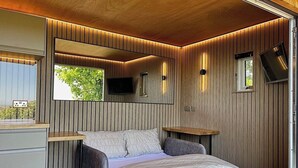 Ein Schlafzimmer mit Bett, Nachttischen, einem Spiegel, einem Fernseher und einem Fenster.
