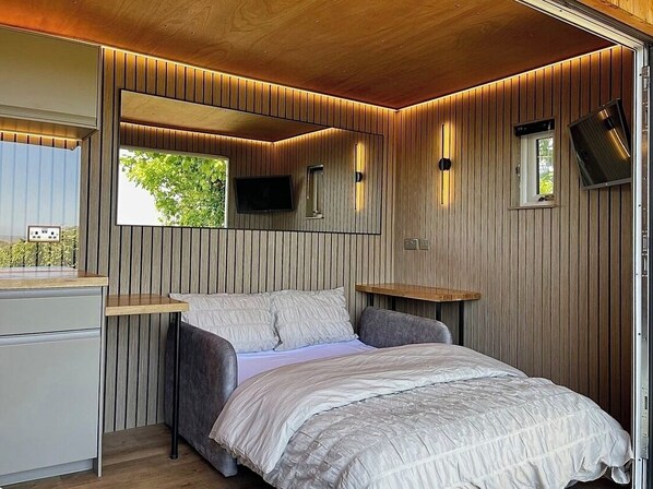 Ein Schlafzimmer mit Bett, Nachttischen, einem Spiegel, einem Fernseher und einem Fenster.