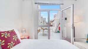 Ein Hotelzimmer mit Bett, Nachttisch, Lampe und Blick auf den Außenbereich des Balkons.