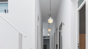 Ein moderner Flur mit weißen Wänden, einem Fischgrätparkett und einer Treppe links.