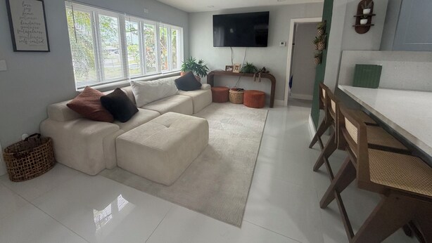 Una sala moderna con un sofá, un televisor de pantalla plana y un comedor con mesa y sillas.