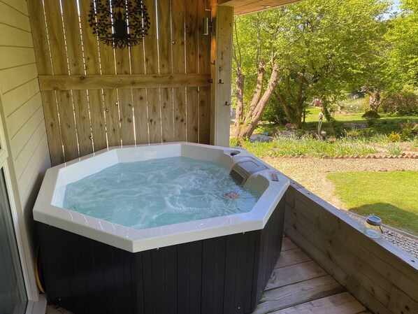 Un jacuzzi con terraza de madera y vista a un jardín.