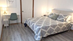 Une chambre à coucher avec un lit, un bureau, une chaise et une porte.