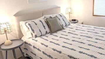 A bedroom with a bed, bedside tables, and a wall-mounted sign.