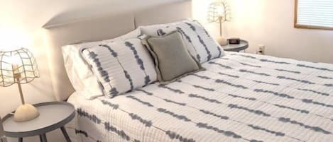 Un dormitorio con cama, mesitas de noche y un cartel en la pared.