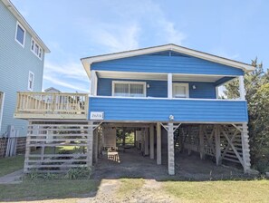 A two-story house with a blue exterior, a covered porch, and a number '26210' on the front.