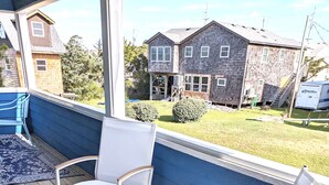 A covered outdoor seating area with two white rocking chairs and a blue wall.