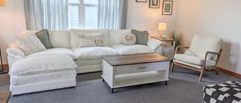 A living room with a sofa set, a coffee table, a chair, and a small ottoman.