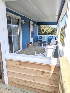 A covered outdoor area with a wooden deck, a sliding glass door, and a table with chairs.