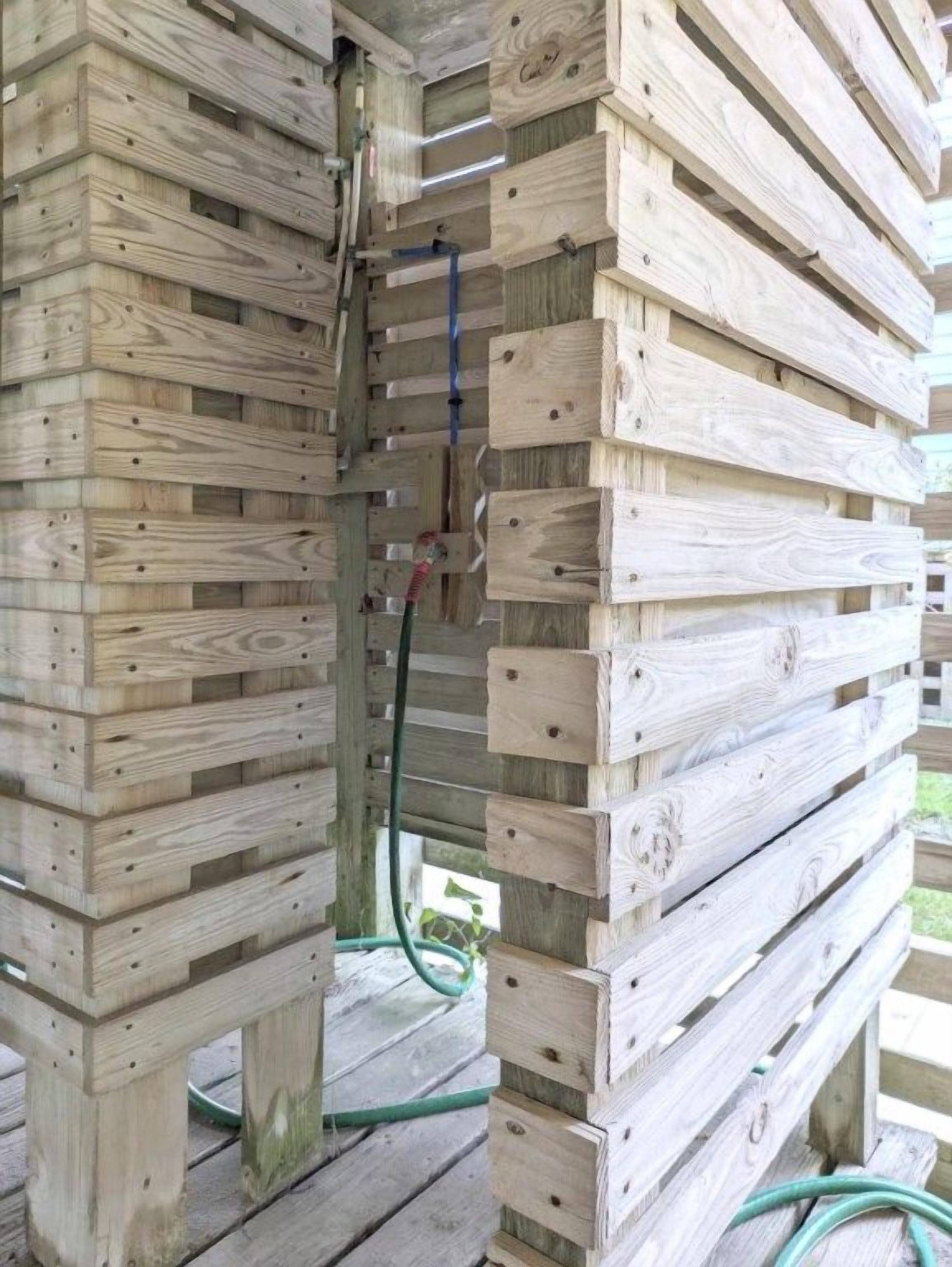Une structure en bois avec des poutres horizontales et un tuyau d’arrosage vert.