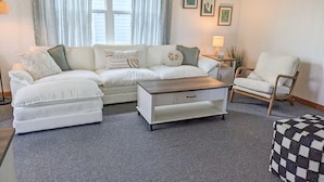 A living room with a sofa, a coffee table, a chair, and a small table with a lamp.