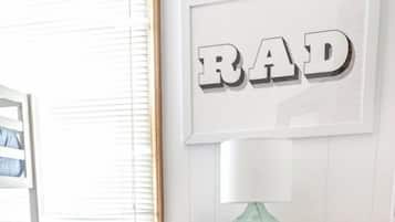 Eine weiße Kommode mit sechs Schubladen, ein gerahmtes Wort 'RAD' an der Wand und eine kleine grüne Vase darauf.