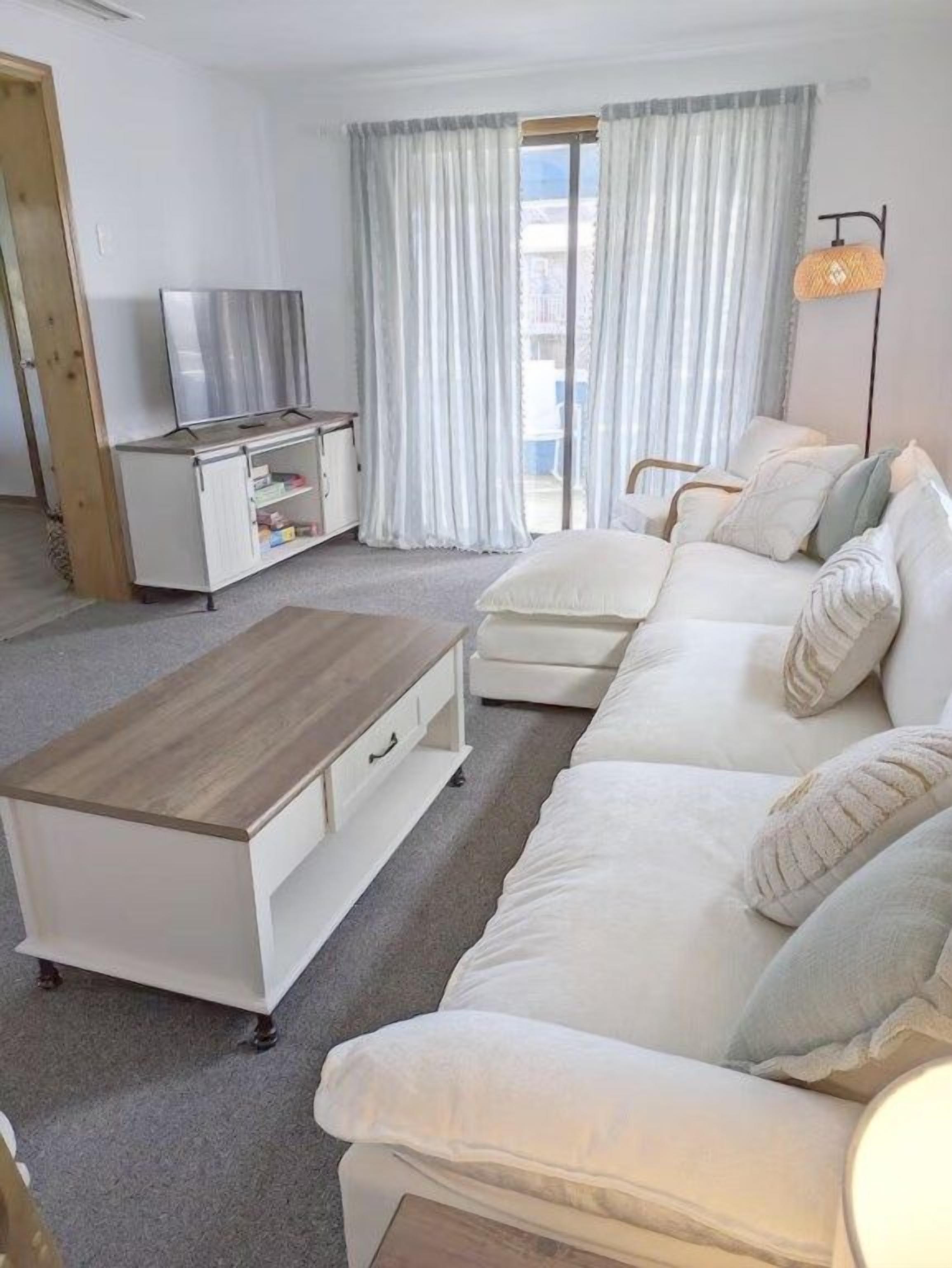 Un salon avec un canapé, une table basse, un téléviseur et une lampe.