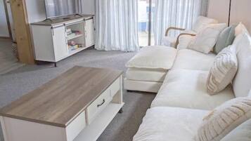 Un salon avec un canapé, une table basse, un téléviseur et une lampe.
