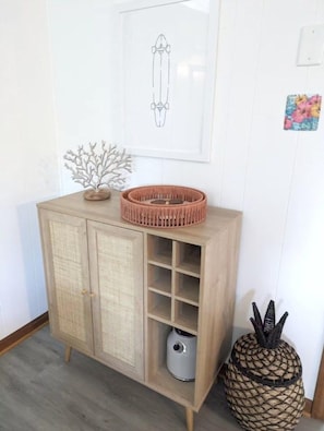 Un mueble de madera con estantes abiertos, un dibujo enmarcado en la pared y una cesta decorativa encima.