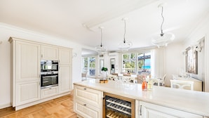 A spacious kitchen with white cabinetry, a built-in wine cooler, and a large island with a wine rack. - Luxury Lake-Front Catullo A2 (Sirmione)