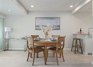 A dining area with a wooden table, four chairs, a vase with flowers, and a painting on the wall. - Montecito Penthouse, 2 + 2, walk to Butterfly Beach & Coast Village Road (Montecito)