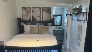 A bedroom with a bed, bedside tables, a dresser, a microwave, and a thermostat. - Cozy Studio in Miramar (Miramar)