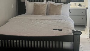 A bedroom with a bed, a nightstand, a mirror, and abstract wall art. - Cozy Studio in Miramar (Miramar)