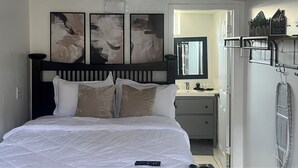 A bedroom with a bed, a bedside table, a mirror, and artwork on the wall. - Cozy Studio in Miramar (Miramar)
