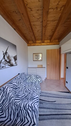 Un dormitori amb un llit daurat, un sostre de fusta, un quadre emmarcat i una porta.