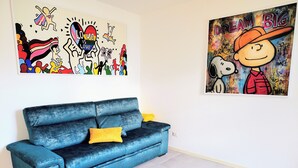A blue sofa with a yellow pillow in a room with a white wall.