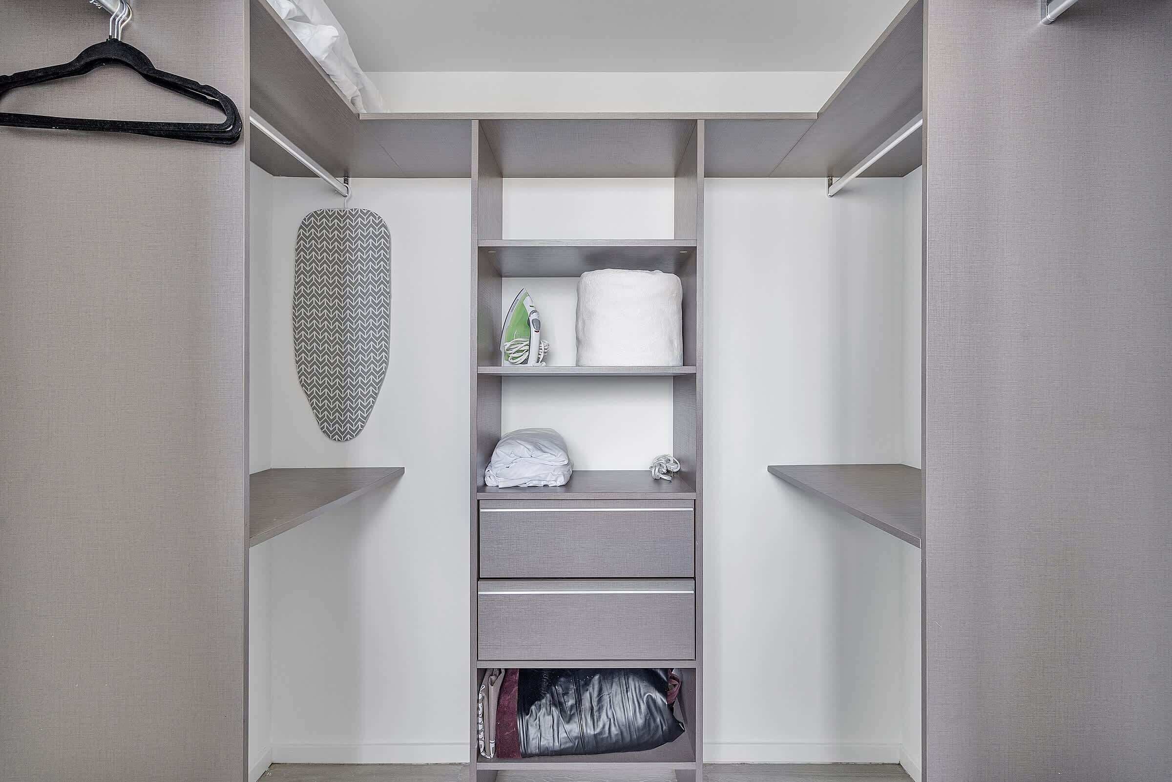 Un dressing accessible sans porte, avec des étagères ouvertes, un vêtement suspendu et un article plié.