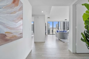 Ein modernes Interieur mit einem Flur, der in einen Wohnbereich mit Blick auf die Stadt führt.
