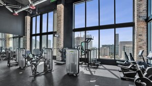 A gym with various exercise equipment, large windows, and a view of the cityscape. - X Lounge VIII-Prime Corner Residence (Miami)