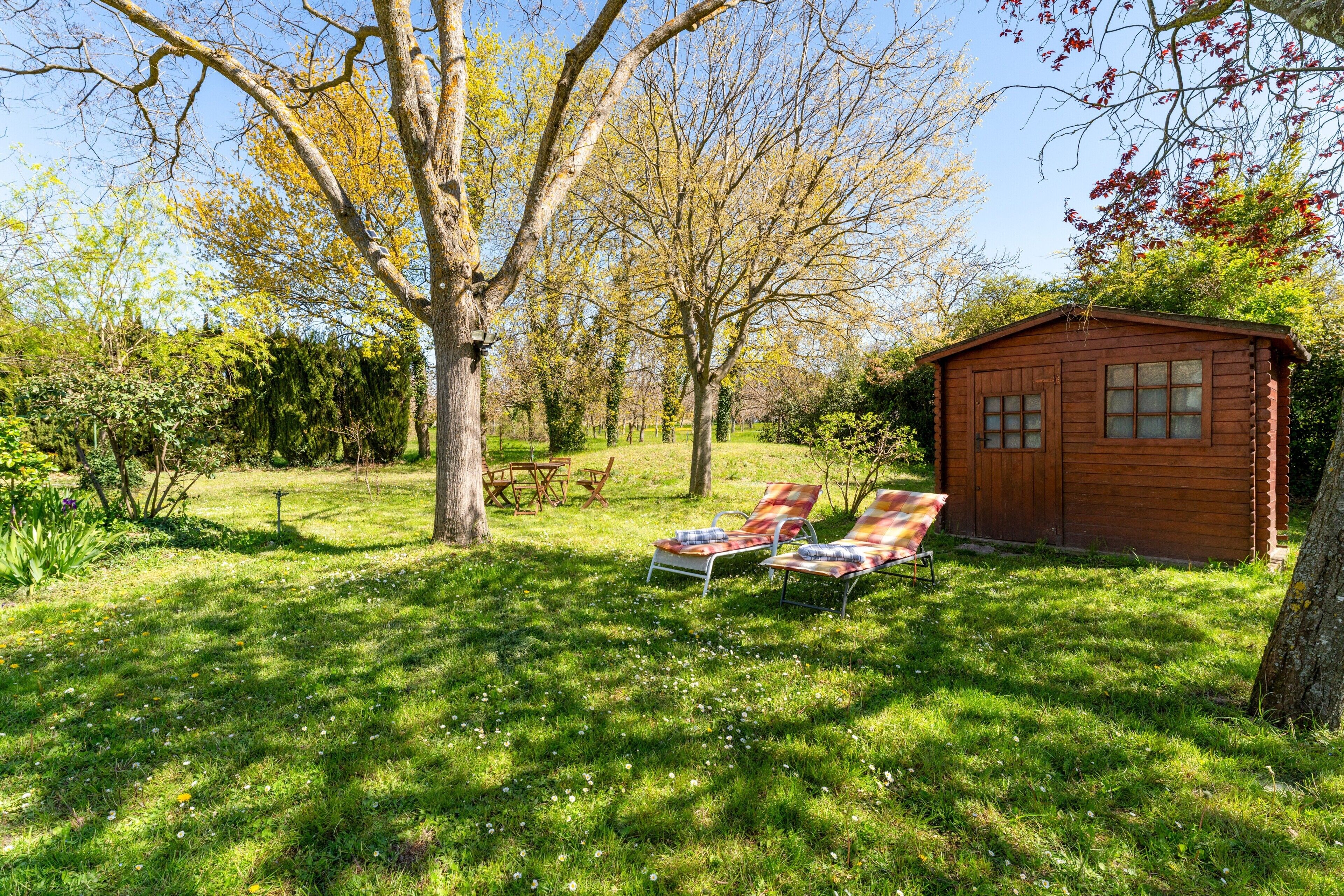 Una cabaña de madera con dos sillones y una pequeña mesa en un jardín trasero con césped.