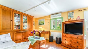 Une chambre avec un lit, des armoires en bois, une télévision et une table décorée de fleurs.