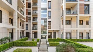Een meerlaags woongebouw met een centrale trap, balkons en goed onderhouden hagen.