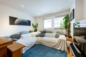 Un salon moderne avec un canapé, une table en bois et un grand tableau représentant une planète.