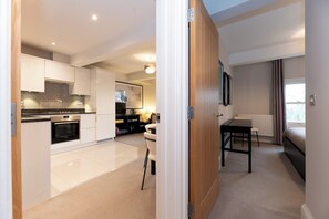 A modern kitchen with white cabinets, a built-in oven, and a dining area with a table and chairs. - Stunning 1 BR Surbiton with views, near station - Pass the Keys (Surbiton)