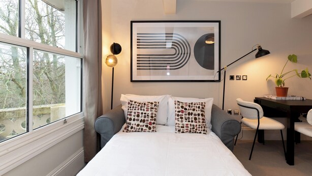 A modern hotel room with a large bed, a desk, and a potted plant. - Stunning 1 BR Surbiton with views, near station - Pass the Keys (Surbiton)