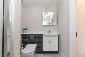 Ein modernes Badezimmer mit Toilette, Waschbecken und Spiegel.