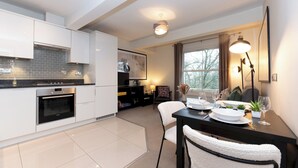 A modern kitchen with white cabinets, a built-in oven, and a dining area with a table set for two. - Stunning 1 BR Surbiton with views, near station - Pass the Keys (Surbiton)