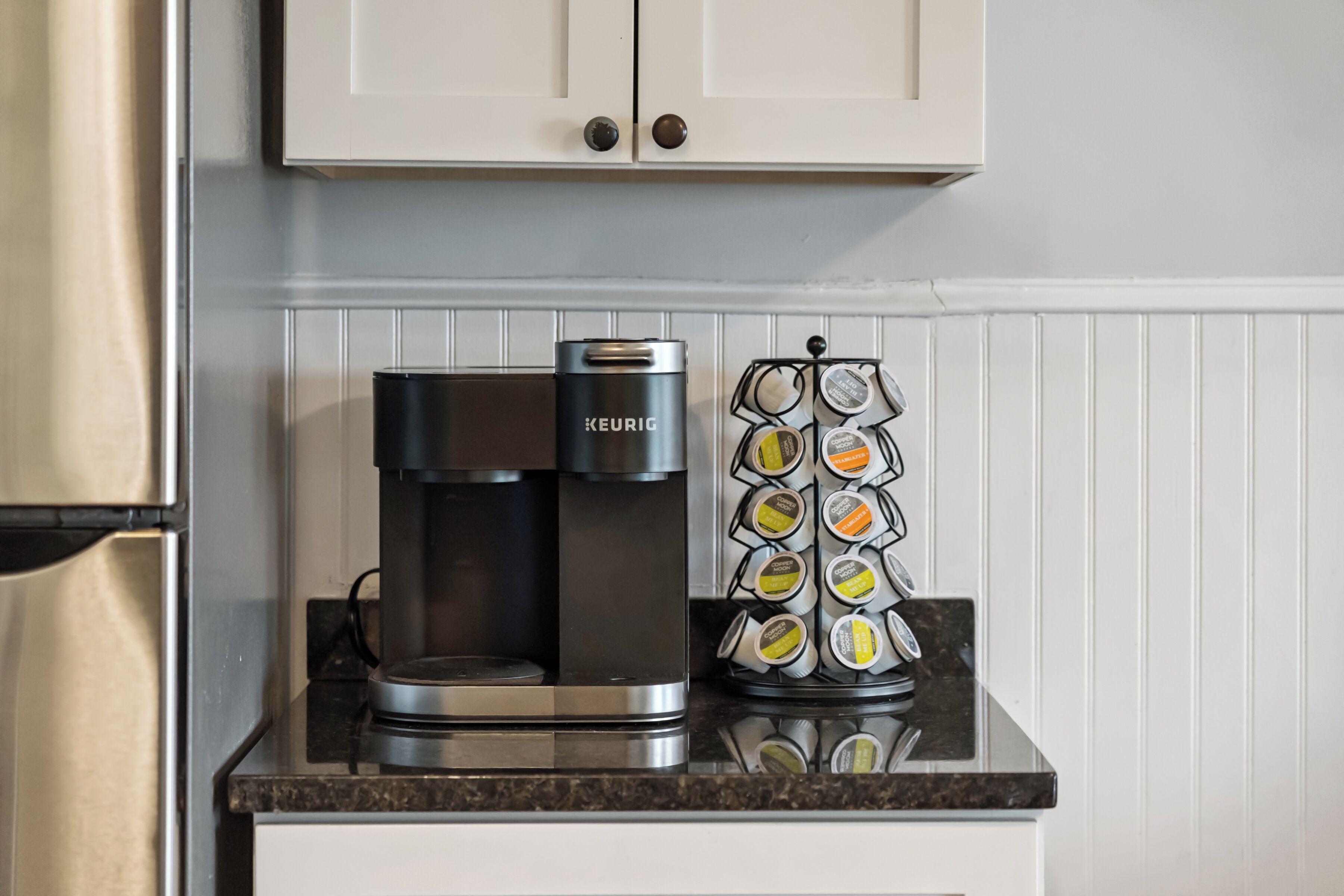 Een koffiezetapparaat en een houder voor koffiecups op een aanrecht.