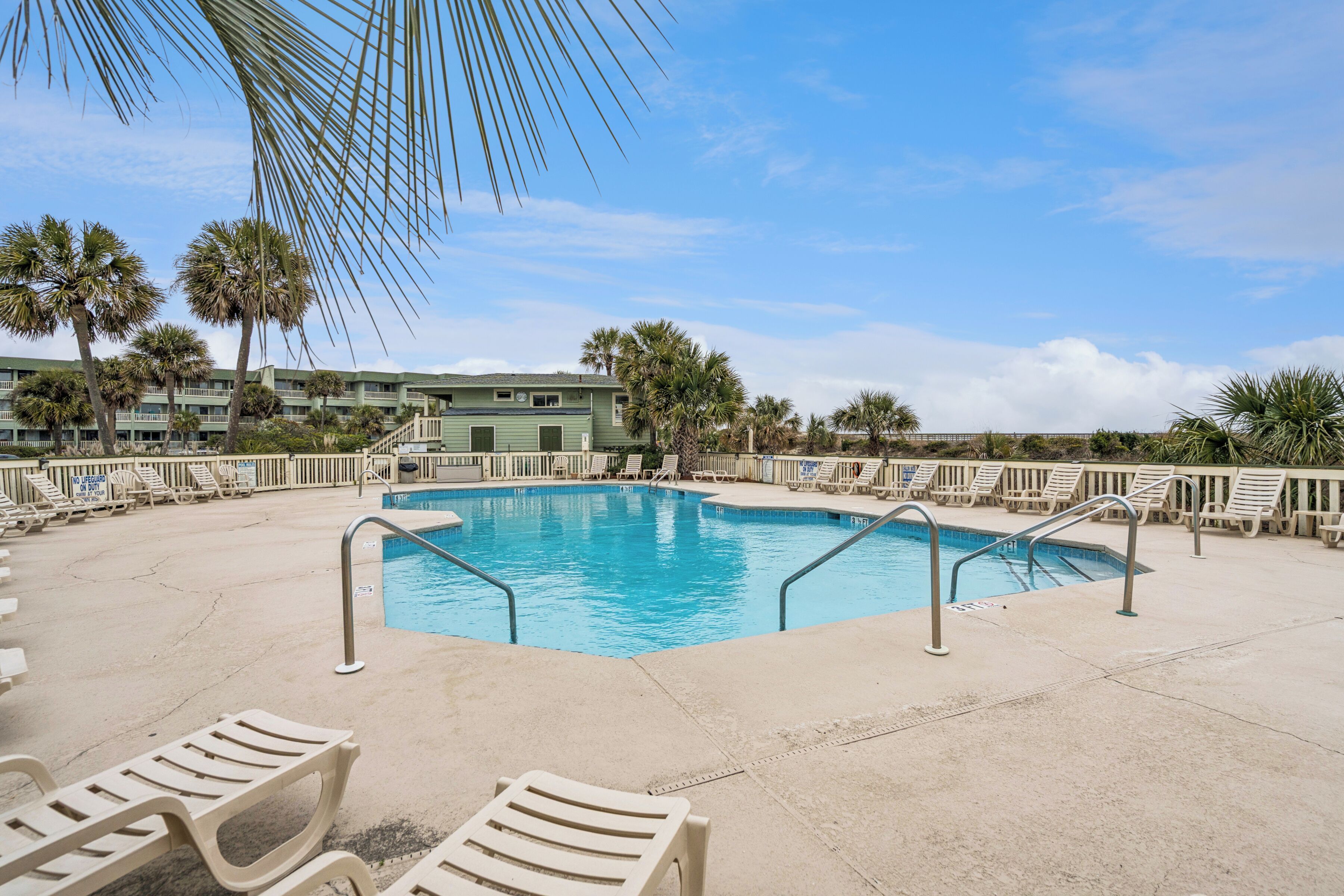 A pool area with lounge chairs and palm trees.