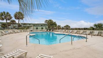 A pool area with lounge chairs and palm trees.