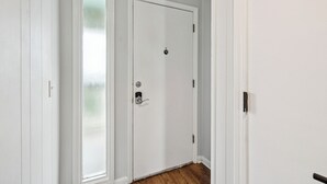 Ein Flur mit zwei weißen Türen, eine davon mit einer satinierten Glasverkleidung, und einem Holzboden.
