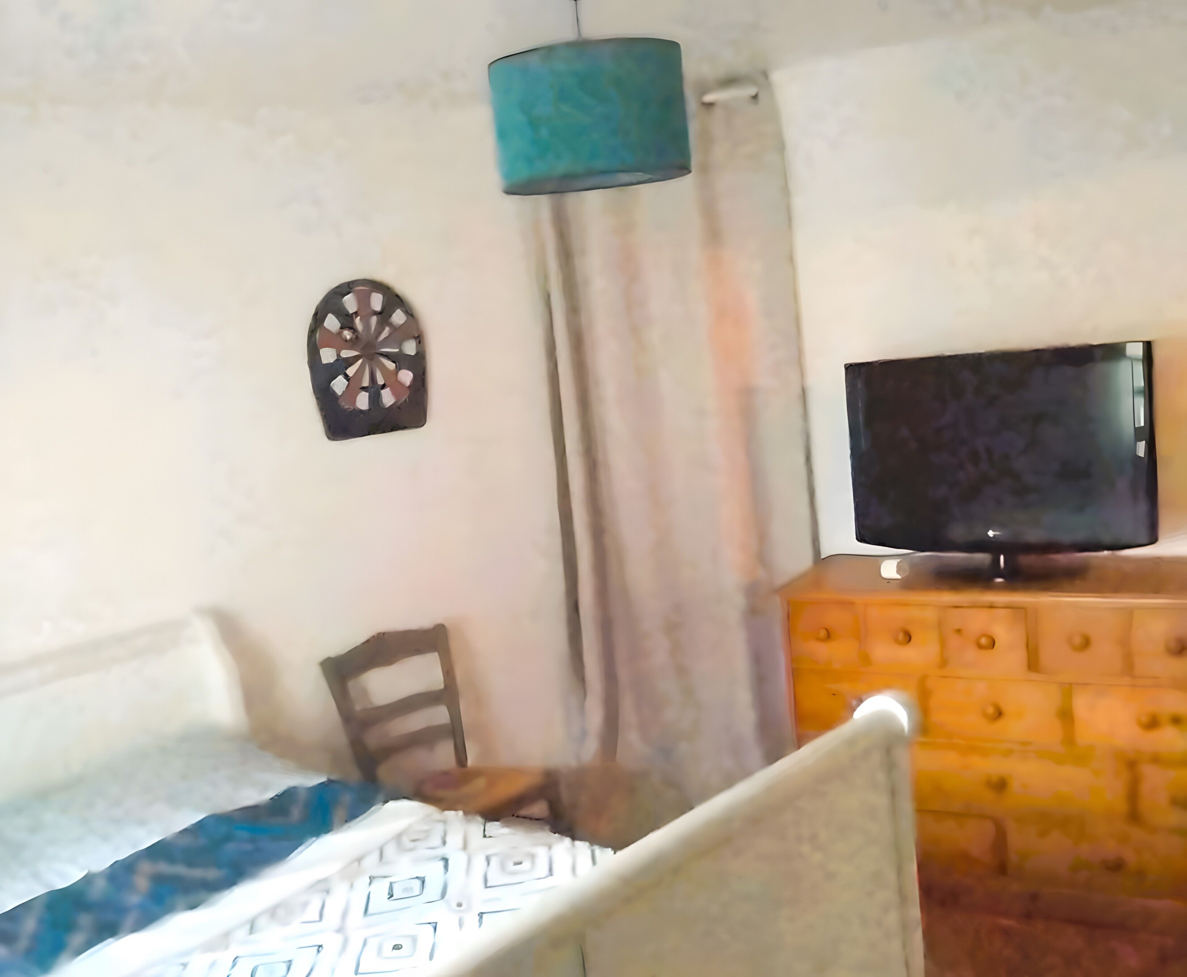 Ett sovrum med en säng, en tv på en byrå, en väggdekoration och en gardin.