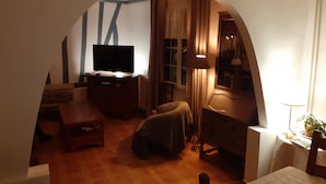 Un salon confortable avec un téléviseur, un canapé, un fauteuil et une table.