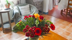 Une chambre comprenant un lit, une table de chevet, une lampe et une table agrémentée d’un arrangement floral.