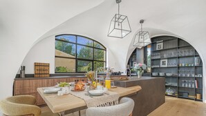 Une cuisine moderne avec un îlot central, des chaises en bois et un coin repas pour le petit-déjeuner.